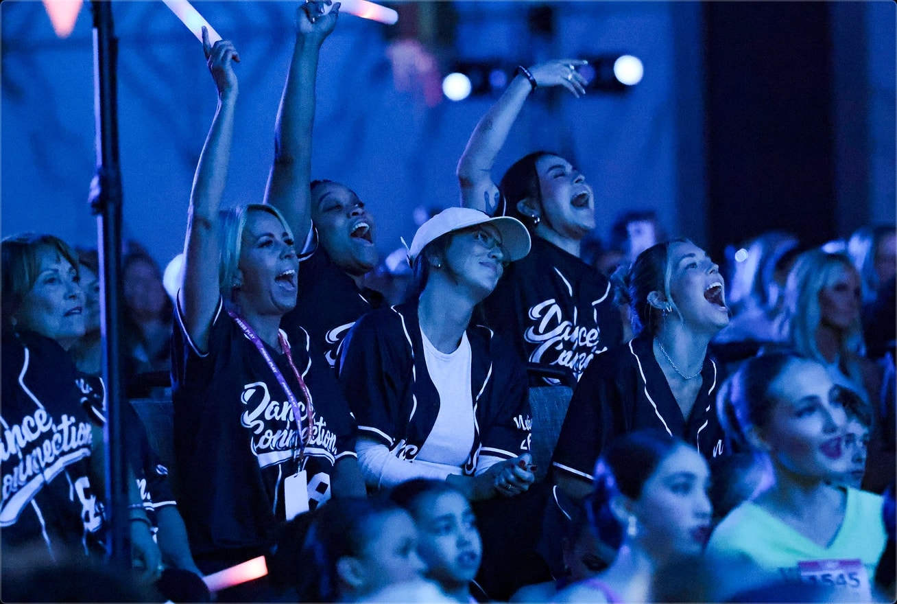 Studio dancers cheering in the audience with glow sticks
